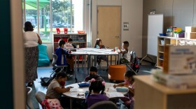 Students sit at circle tables and fill out worksheets.