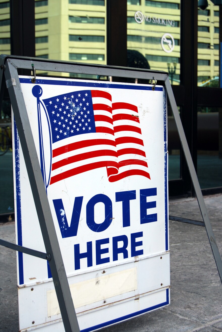 "Vote here" sign with an American flag