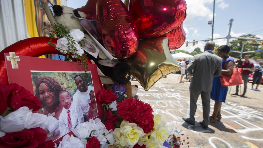 A photo of Alton Sterling and his family is displayed at a memorial outside the Triple S Mart on Thursday in Baton Rouge, La. Sterling was shot by a police officer in front of the convenience store on Tuesday.