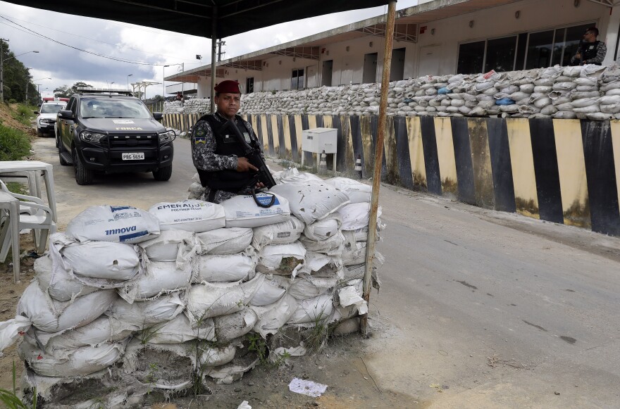 A Brazilian police officer stands guard at the entrance of the Anísio Jobim Penitentiary Complex in Manaus, Brazil, Tuesday. Dozens of inmates were killed in different prisons in Amazon state on Sunday and Monday.