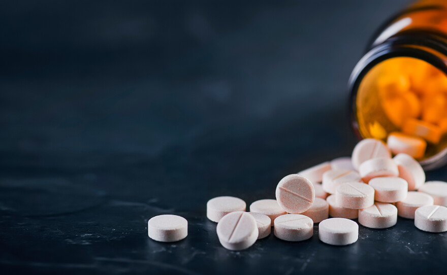 White medical pills or tablets with bottle on black background.