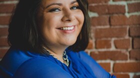 Headshot of Christina Santiago in blue shirt in front of brick wall.