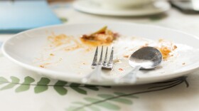 Empty white dish with fork and spoon after eating on the table.