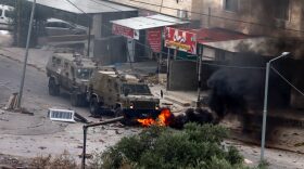 Tires burn beneath Israeli security forces armoured vehicles during a raid in Jenin in the occupied West Bank.