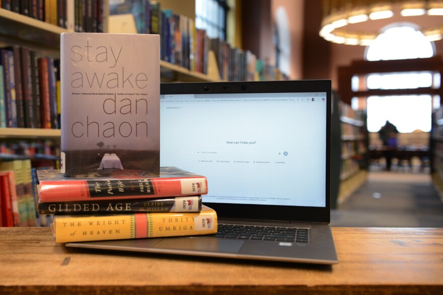 A laptop computer next to a stack of books