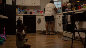 Vicki Lightfoot washes dishes while Maurice plays on the floor by her side early in the morning before school. Lightfoot was solely responsible for getting all four children ready for daycare and school.