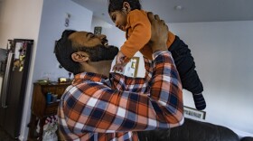 Dr. Rajandeep Singh Paik lifts his nine-month-old son Siraj after getting home from work. (Jesse Costa/WBUR)
