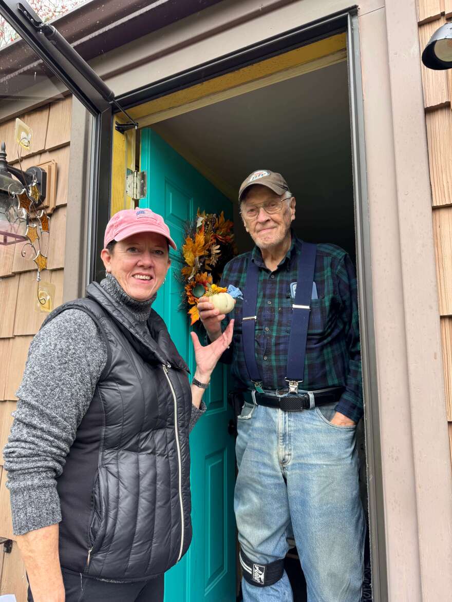 Jan Olson (volunteer delivery driver) delivering a Thanksgiving floral arrangement by the Little Compton Garden Club to Butch Wilkie (Senior Luncheon delivery patron).