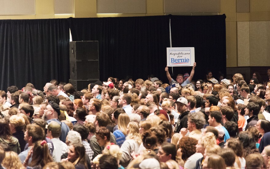 A man holds up a sign that reads, "Republicans for Bernie."