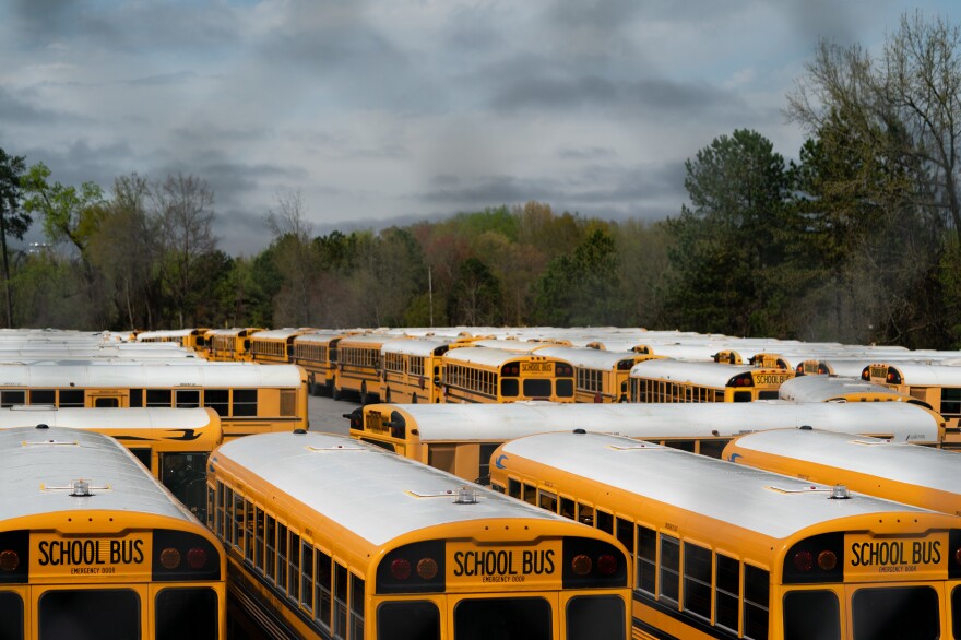 School buses sit parked at a lot in Marietta, Ga., in March. Georgia Gov. Brian Kemp has pushed for students to return to school in the fall, but the state's largest system, in Gwinnett County, has decided on all-virtual learning.