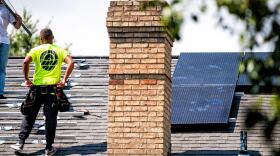 A worker installs rooftop solar panels on a home in Northern Virginia. (Image via Shutterstock)