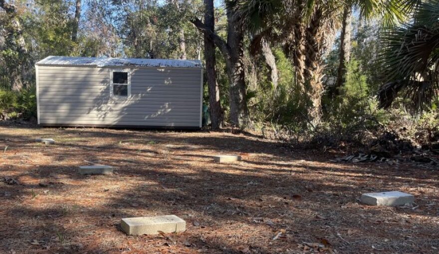 A shed in a backyard with bricks on the ground