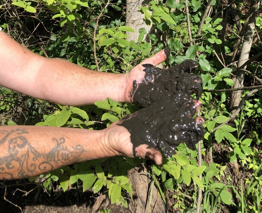 Close up of hands holding dark, runny muck in both palms