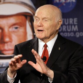 John Glenn speaks in front of an image of him as an astronaut in 1962.