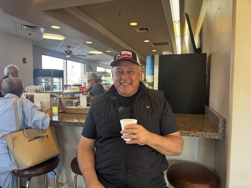 Jaime Ramirez holds his hot cup of coffee and smiles at the camera.