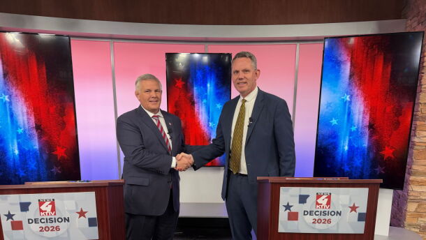 Two political candidates shake hands before a political debate. One on the left is shorter than the man on the right.