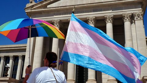 A person holds a transgender flag and a rainbow umbrella during a rally outside the Oklahoma State Capitol in Oklahoma City on March 14, 2024.