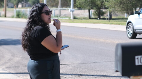 A woman stands beside the street leading to National Beef Tuesday, blowing a whistle and warning workers of federal immigration agents.