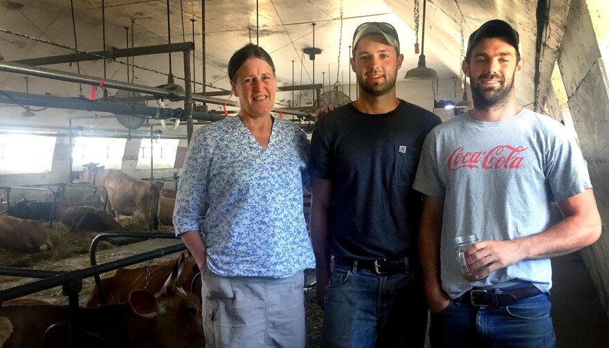 Edie Griffiths stands in the barn with Mark and Zeal Dunphy, whose family is taking over Seven Stars Farm. (Robin Young/Here & Now)