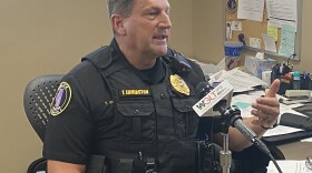 Police officer sits at his desk speaking into a microphone