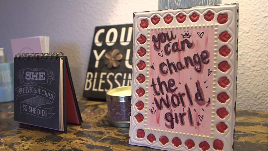 Various signs and artwork with positive affirmations. One sign in the foreground is legible and says you can change the world, girl.