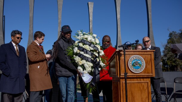 City Council member Kevin Spears, left, and Atiba Johnson, right, Vice Chairman for the City of Wilmington Commission on African-American History, move the memorial wreath to the front of the podium during the Commemoration of the 127th Anniversary of the 1898 Massacre Wreath Laying Ceremony at the 1898 Memorial Park in downtown Wilmington on November 10, 2025.