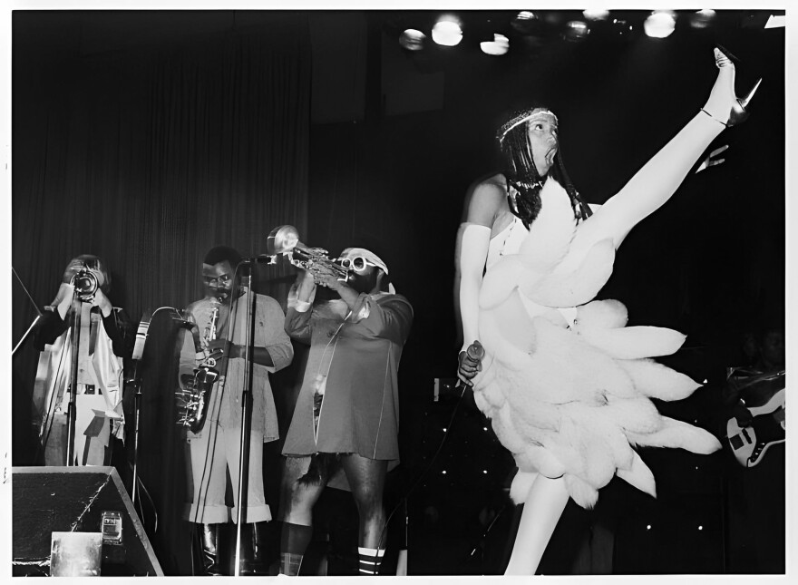 Bride Dawn Silva high-kicks in Amsterdam with the Horny Horns (Rick Gardner, Maceo Parker, and Richard “Kush” Griffith) onstage in December 1978