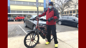 41-year-old Jeremy Hurt poses with his red electric bicycle outside of Sultan's Express in Downtown Lansing in January 2022.