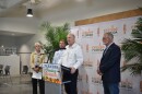 Florida's commissioner of agriculture stands to speak at a lecturn. There's three people beside him and a backdrop that reads "Feeding Florida."