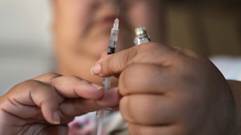 a person holds a needle and a vial of medicine
