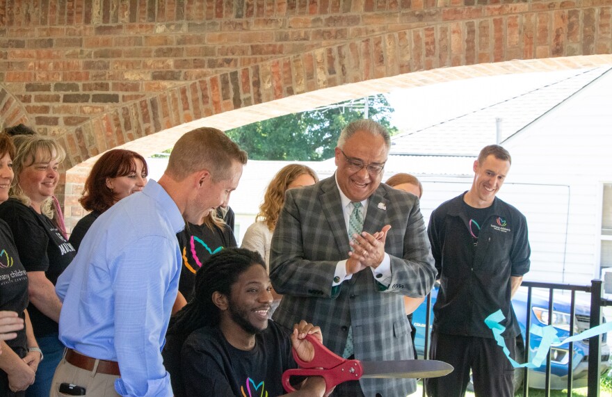 Dewayne Pollard cuts a ribbon outside his new home. He is serving as the pilot resident for the Mattie Homes Project.