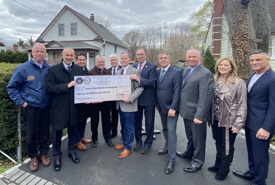 New York State Senator Jim Gaughran and Assemblymember Steve Stern, both Democrats, present a check for $22 million to Huntington Station homeowner, Willie Perez.