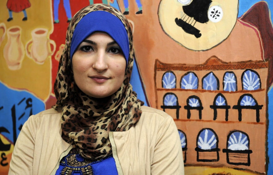 Linda Sarsour, director of the Arab American Association of New York, poses for photos in front of a canvas painted by the association's youth group at its headquarters in the Brooklyn borough of New York in December 2011. (Henny Ray Abrams/AP)