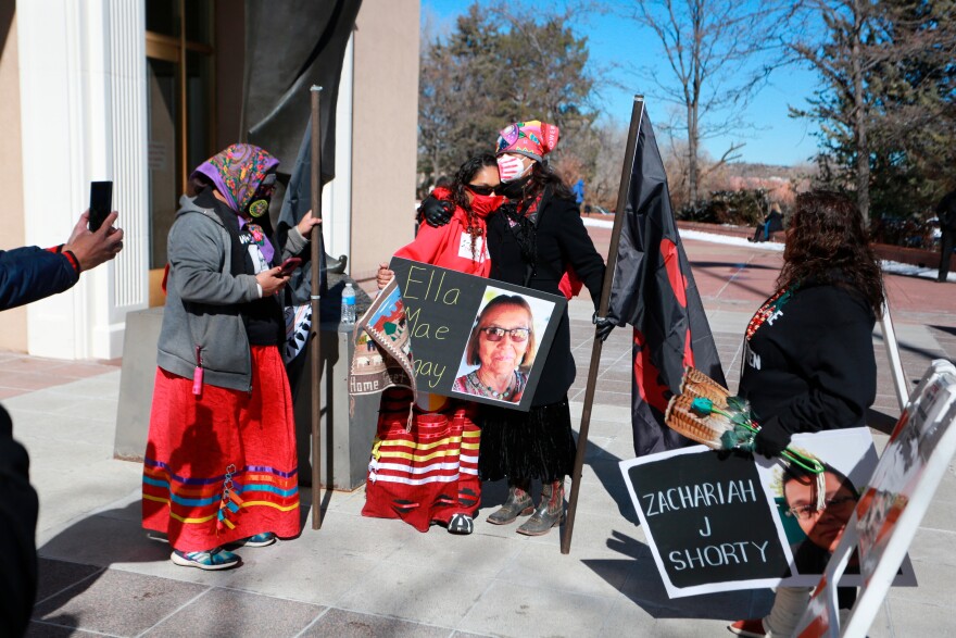Seraphine Warren, center left, is embraced by state New Mexico state Sen. Shannon Pinto while holding a poster with Warren's aunt Ella Mae Begay's photo on it outside the state capitol building Feb. 4, 2022, in Santa Fe, N.M.