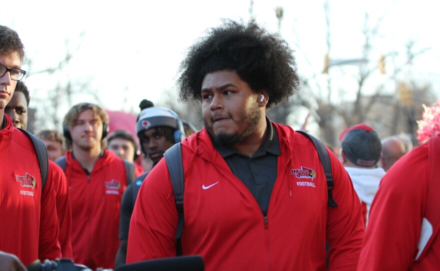 Fans and marching band members greet ISU football players and coaches