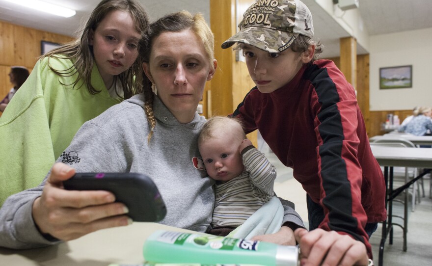 Trista Bonus (left) watches a news clip about the nearby mudslide with LoAnna Langton and her sons at a temporary Red Cross shelter in Darrington on Sunday. The Langton home was flooded by waters from the Stillaguamish River, which was partially blocked by the mudslide.