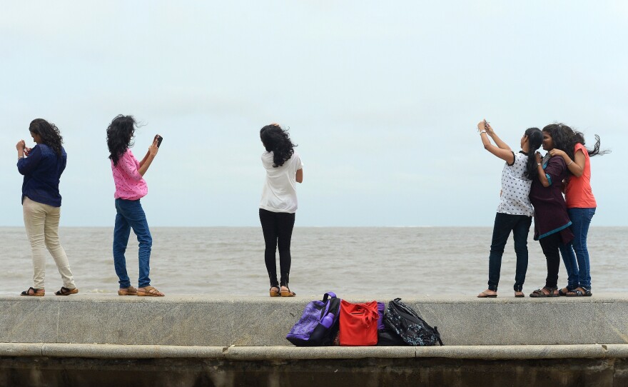 In this photograph taken on June 15, 2015, young Indian students take 'selfies' on Marine Drive promenade in Mumbai.