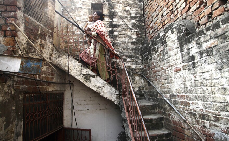 Ashi, 50, a leader of the movement for transgender rights in Pakistan, carries her neighbor's baby upstairs. For more than a century, transgender women were pushed to the margins in Pakistan.