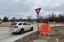 A white SUV drives through a newly constructed roundabout on the south side of Columbia. A orange sign on the right side reads "road work ahead."