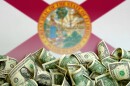 a hill of $1 bills in front of a florida state flag 