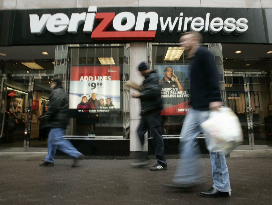 Pedestrians walk past a Verizon Wireless shop.