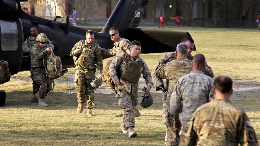 Capt. Casey Wolfe, Capt. John Urquhart, Staff Sgt. Ben Dellinger, Sgt. James Wright - arrive in Kabul as part of Operation Proper Exit for wounded warriors. They are all walking toward the camera. They are greeted by Gen. John Campbell, who is embracing Wright.