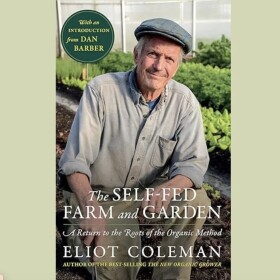 Eliot Coleman on his book cover with rows of crops behind him in a greenhouse