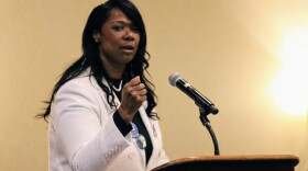 A woman shaking her fist while standing behind a microphone and lectern.