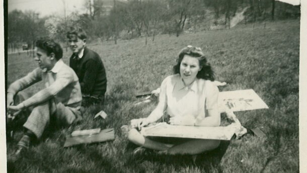 a woman and two men sit on a grassy lawn in a black and white photo