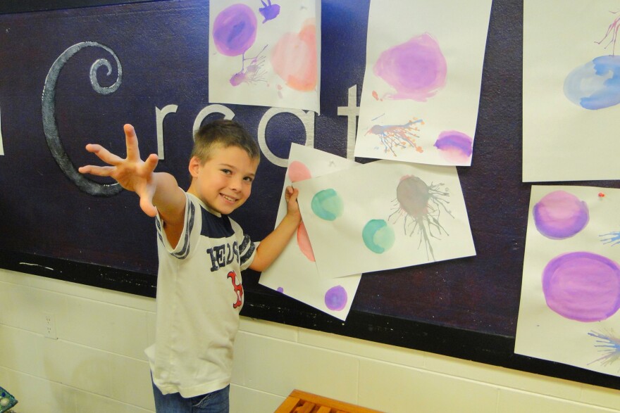 An Osceola Arts summer camp student displays visual arts creations.