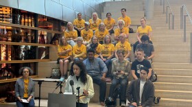 A group of activists stand behind a podium for a press conference on the steps inside Seattle City Hall. 