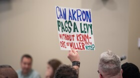  An Akron resident holds a sign at the Akron Board of Education meeting Monday.