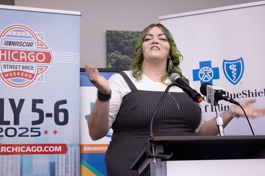 A woman talks into two microphones at a podium