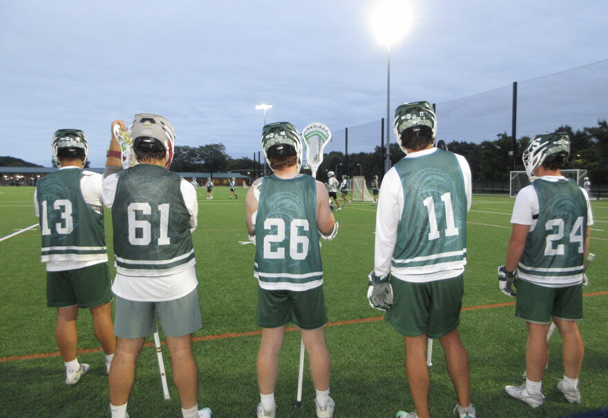 Michigan State club lacrosse players break during practice drills while watching their teammates compete.